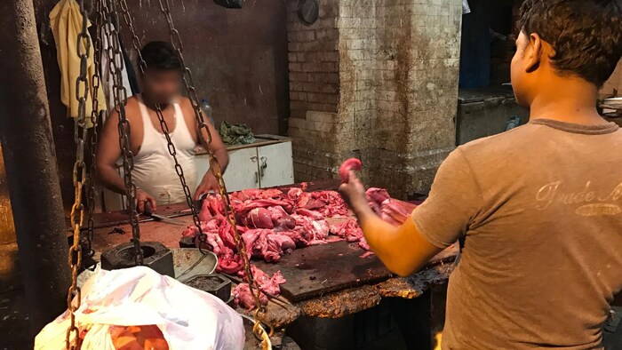Un carnicero corta carne de res en un mercado de carne de Kolkata.