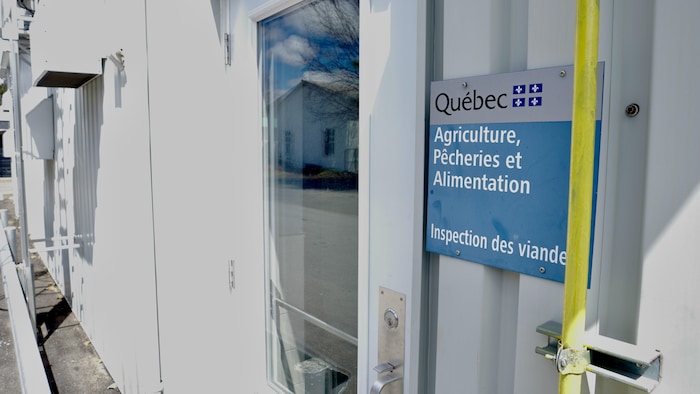 Une affiche d'inspection des viandes du ministère de l'Agriculture, des Pêcheries et de l'Alimentation sur la bâtisse de la Boucherie Alphonse Côté.