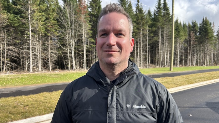 Portrait de Marc-André souriant devant des arbres.