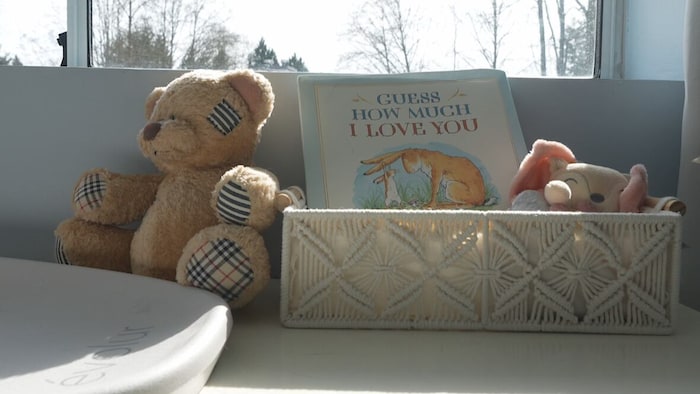 Un ourson et un livre sont disposés dans une chambre de bébé au bord d'une fenêtre.