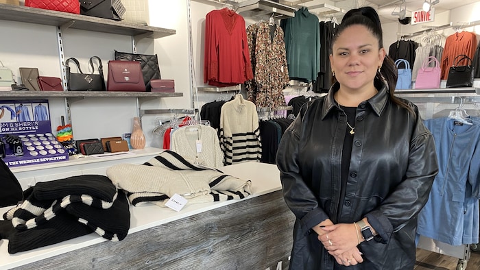 Émilie Gauthier devant un présentoir de vêtements.