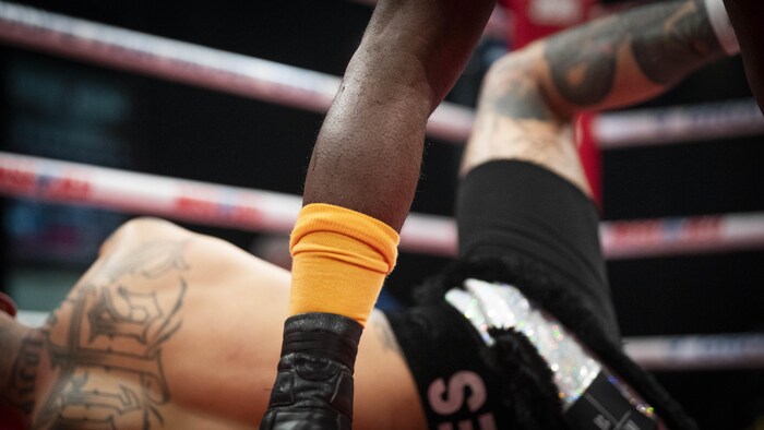 Un boxeur est couché au tapis pendant que son adversaire est debout.