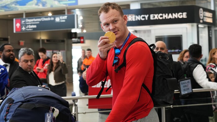 Le capitaine des Sénateurs d'Ottawa Brady Tkachuk montre sa médaille d'or à l'aéroport.