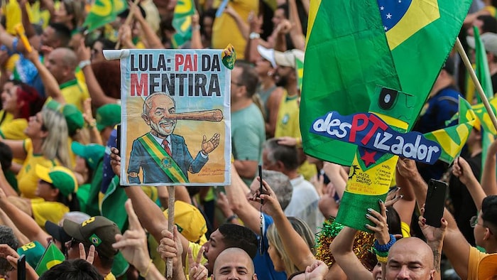 Des partisans de Flavio Bolsonaro brandissent une photo représentant le président brésilien Luiz Inácio Lula da Silva dans un rassemblement.