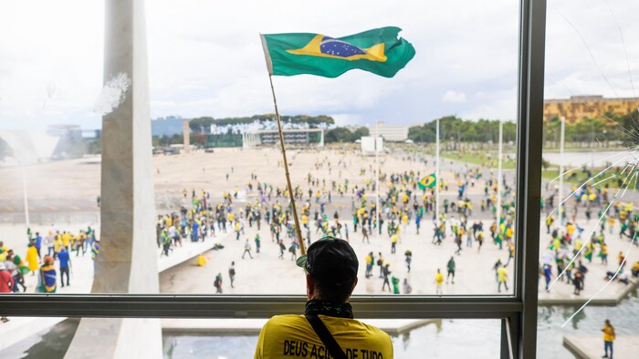 Un émeutier brandit un drapeau du Brésil.