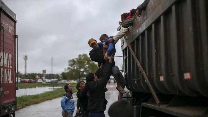 Des habitants aident un enfant à monter dans un camion de secours.