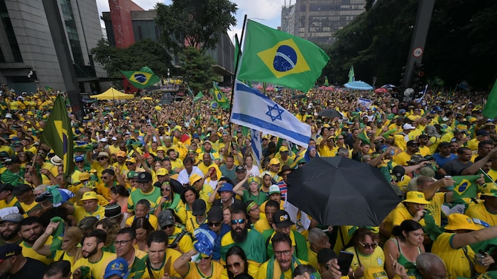 Milhares de pessoas vestidas de amarelo e verde estão reunidas e algumas agitam bandeiras gigantes do Brasil e de Israel.