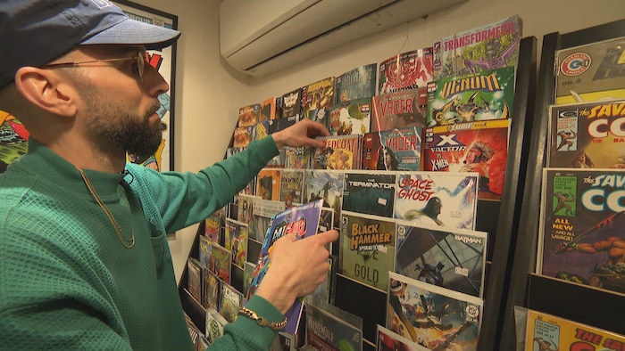 Un homme devant un présentoir rempli de bandes dessinées.
