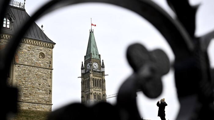 Une personne prend une photo sur la Colline du Parlement alors que le drapeau de la Tour de la Paix flotte en berne après le décès de l'ancien premier ministre Brian Mulroney, à Ottawa, le vendredi 1er mars 2024.
