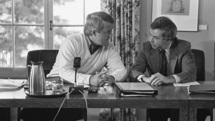 Brian Mulroney et Joe Clark discutent assis à un bureau.