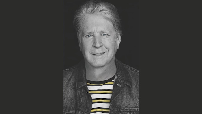 Portrait sur fond noir du musicien, souriant légèrement.
