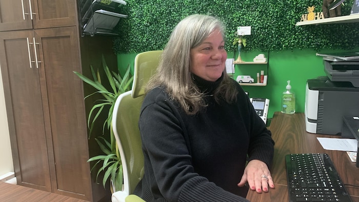 Brigitte Mazerolle Arseneau assise à un bureau.