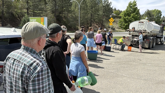 Des gens attendent pour remplir des bouteilles d'eau.