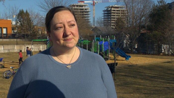 Une femme devant la caméra dans un parc pour enfants.