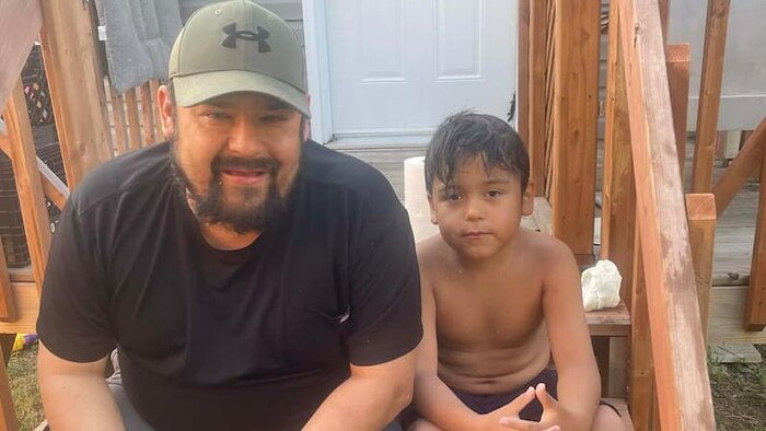 Un homme et un enfant sont assis dans les marches d'un patio. 