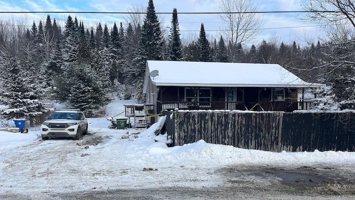 Une auto de la GRC stationnée à côté d'une maison, l'hiver.