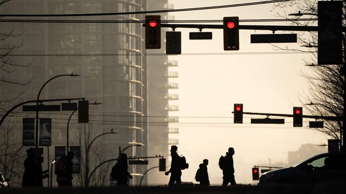 Des piétons au centre-ville de Vancouver, alors qu'un épais brouillard recouvre la ville, le 19 janvier 2026.