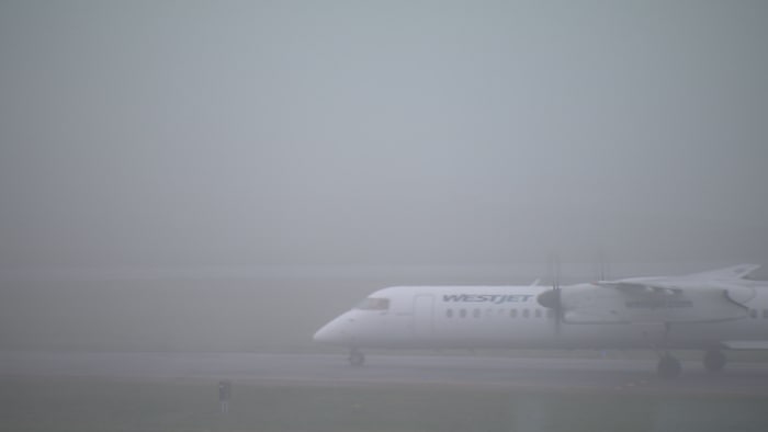 Un avion sur une piste de l'Aéroport international de Vancouver, dans un épais brouillard qui recouvre la ville, le 19 janvier 2026.
