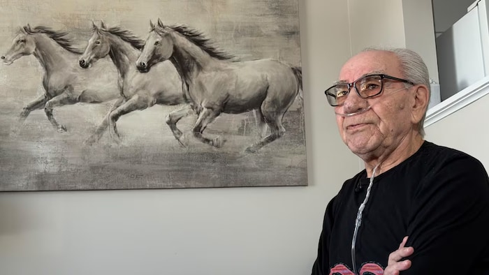 Bruce Flamont dans un établissement avec un portrait de chevaux derrière lui.