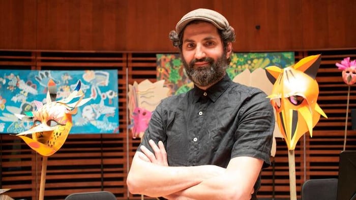 L'artiste se tient debout, les bras croisés. 