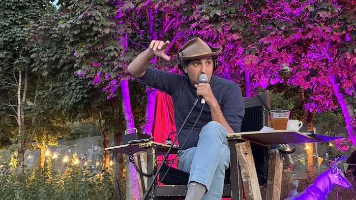 L'homme est sur une chaise haute et donne des indications au micro.