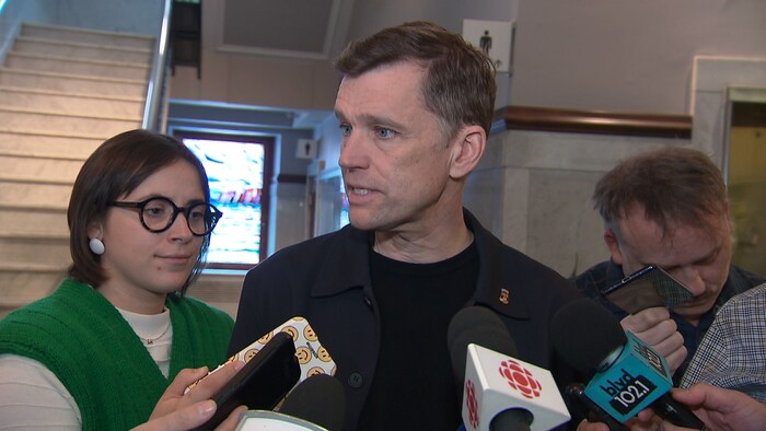 Un homme répond à des questions dans le hall de l'hôtel de ville. 