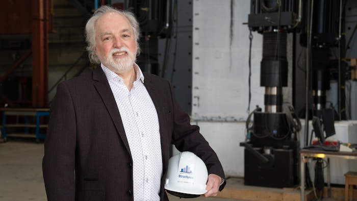 Un homme tient un casque de construction dans un laboratoire.