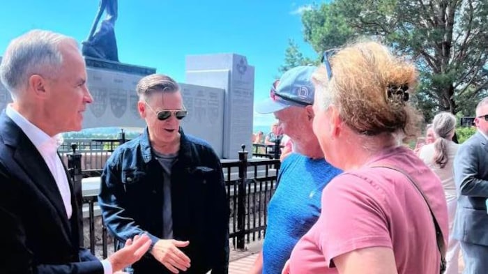 Le premier ministre Mark Carney et le musicien Bryan Adams serrent des mains au monument Terry Fox de Thunder Bay.