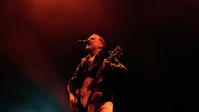 Un chanteur tenant sa guitare sur scène.