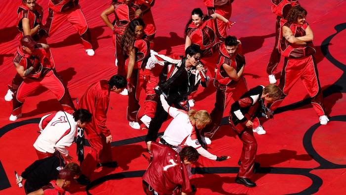 Des gens vêtus de rouge dansent autour d'un chanteur.