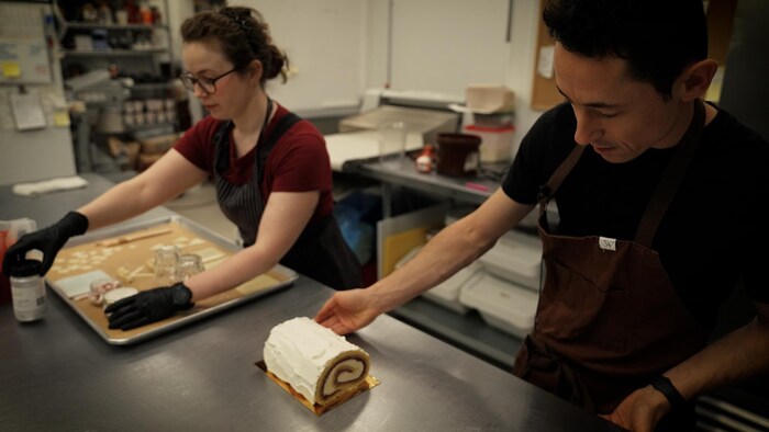 Deux pâtissiers finissent l’assemblage d’un dessert dans une cuisine
