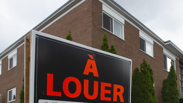 Une pancarte « À louer » devant un immeuble à logements.