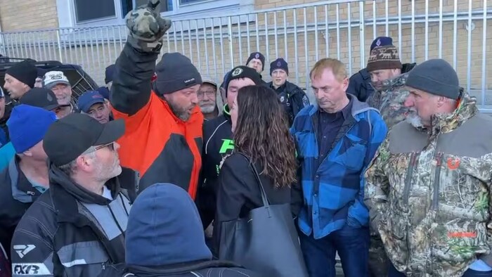 Un pêcheur pointe du doigt et parle avec véhémence à Meghan McCabe entourée d'une dizaine de manifestants. 
