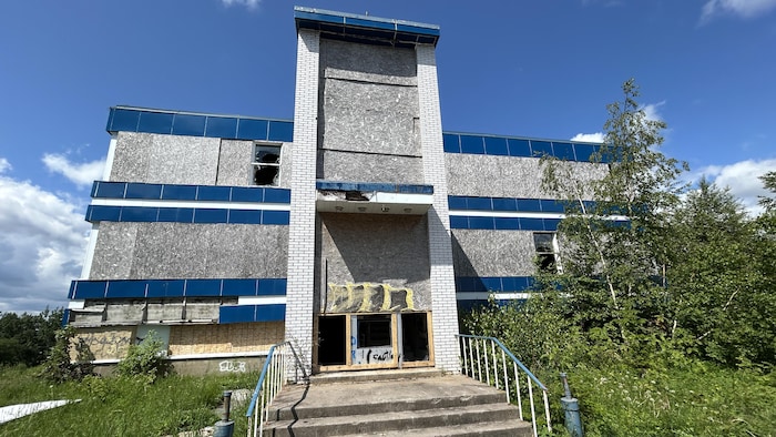 La façade arrière du bureau bleu à Port-Cartier avec les vitres cassées.