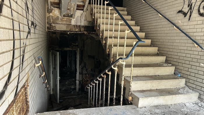 Une cage d'escaliers détériorée où il y a de la vitre au sol.