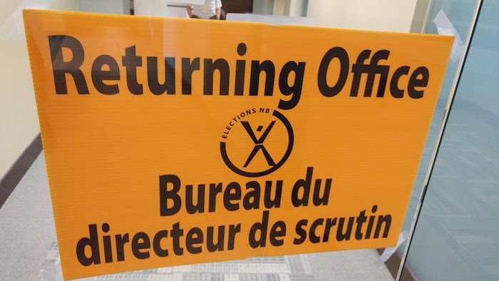 Un affiche jaune indique que l'on entre dans les bureaux du directeur de scrutin. 