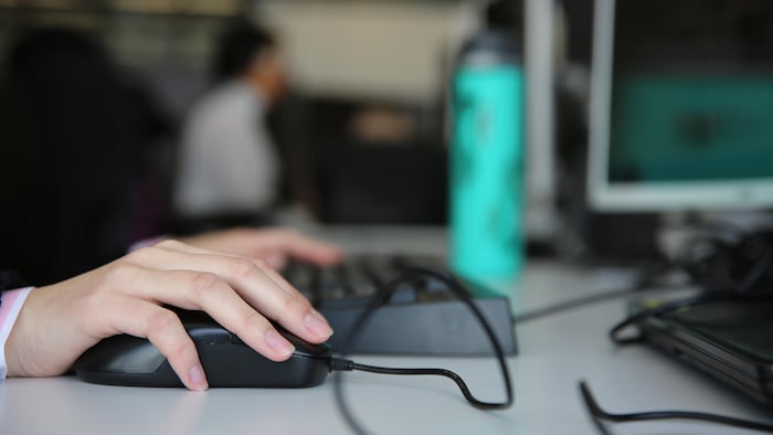 Une main sur une souris d’ordinateur.