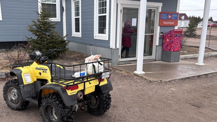Un quatre-roues est stationné devant le bureau de poste. 