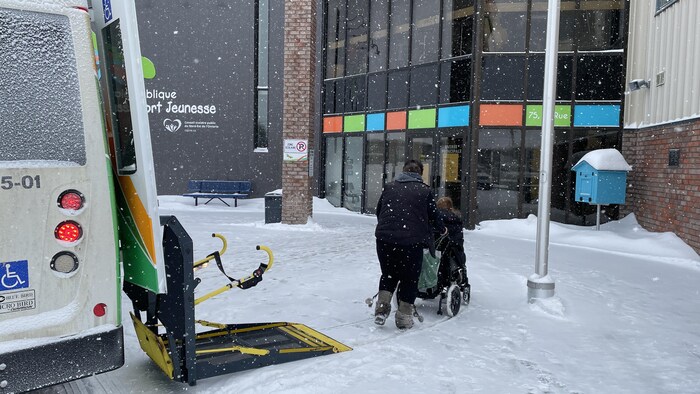 Une dame pousse une autre femme en fauteuil roulant vers le bureau de scrutin à la Place des arts de Hearst.