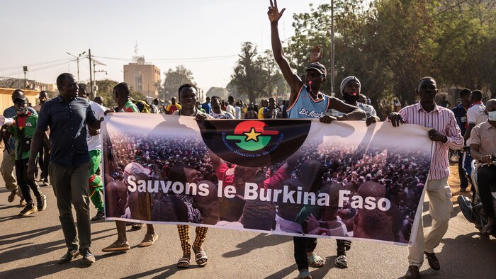 Des manifestants tiennent une banderole.