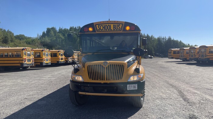 Un autobus scolaire est garé et ses feux orange sont allumés.