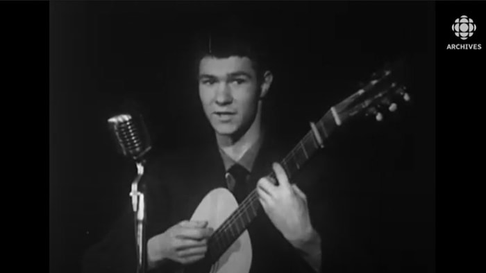 Robert Charlebois chante en tenant sa guitare.