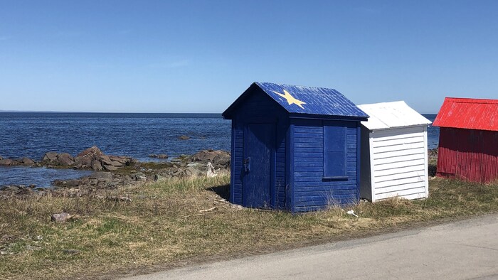 Trois cabanes aux couleurs de l'Acadie sur le bord de la baie des Chaleurs.