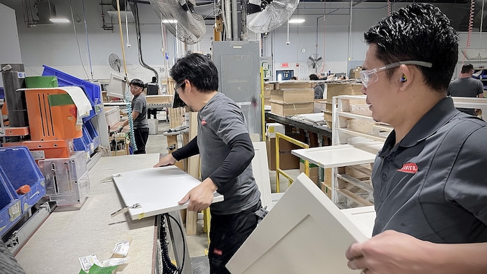 Trois employés assemblent des armoires.