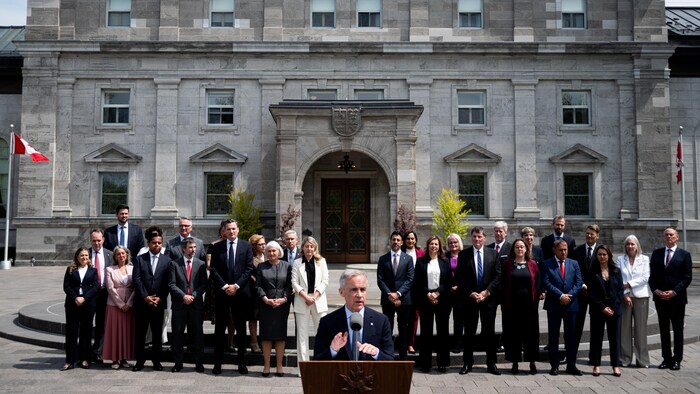 Les membres du nouveau Cabinet du premier ministre Mark Carney le regardent s'adresser aux journalistes.