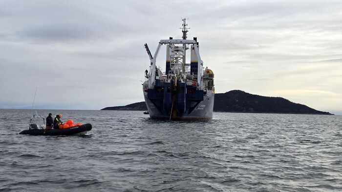 Un grand bateau pose un câble dans l'archipel de Sept-Îles.