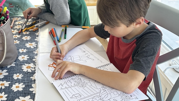 Un garçon fait du coloriage sur un carnet.