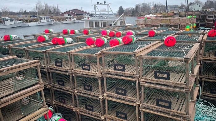 Des casiers à homards sont empilés sur un quai.