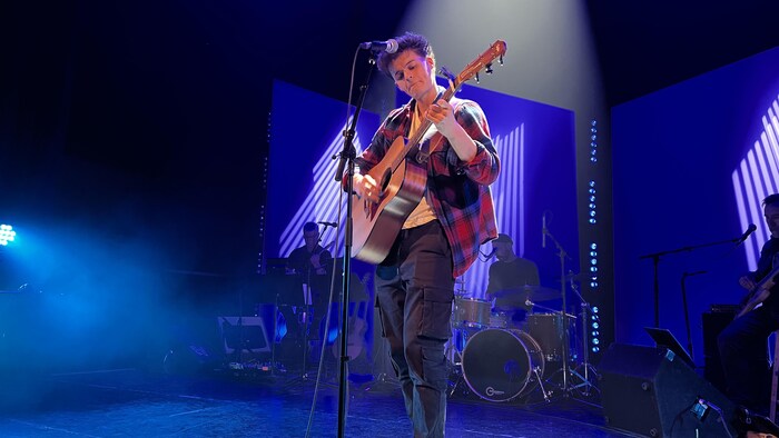 Caleb Dorge sur scène avec sa guitar.