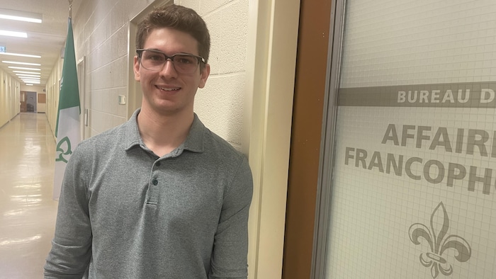Caleb Smith devant la porte du bureau des affaires francophones de l'Université Laurentienne.